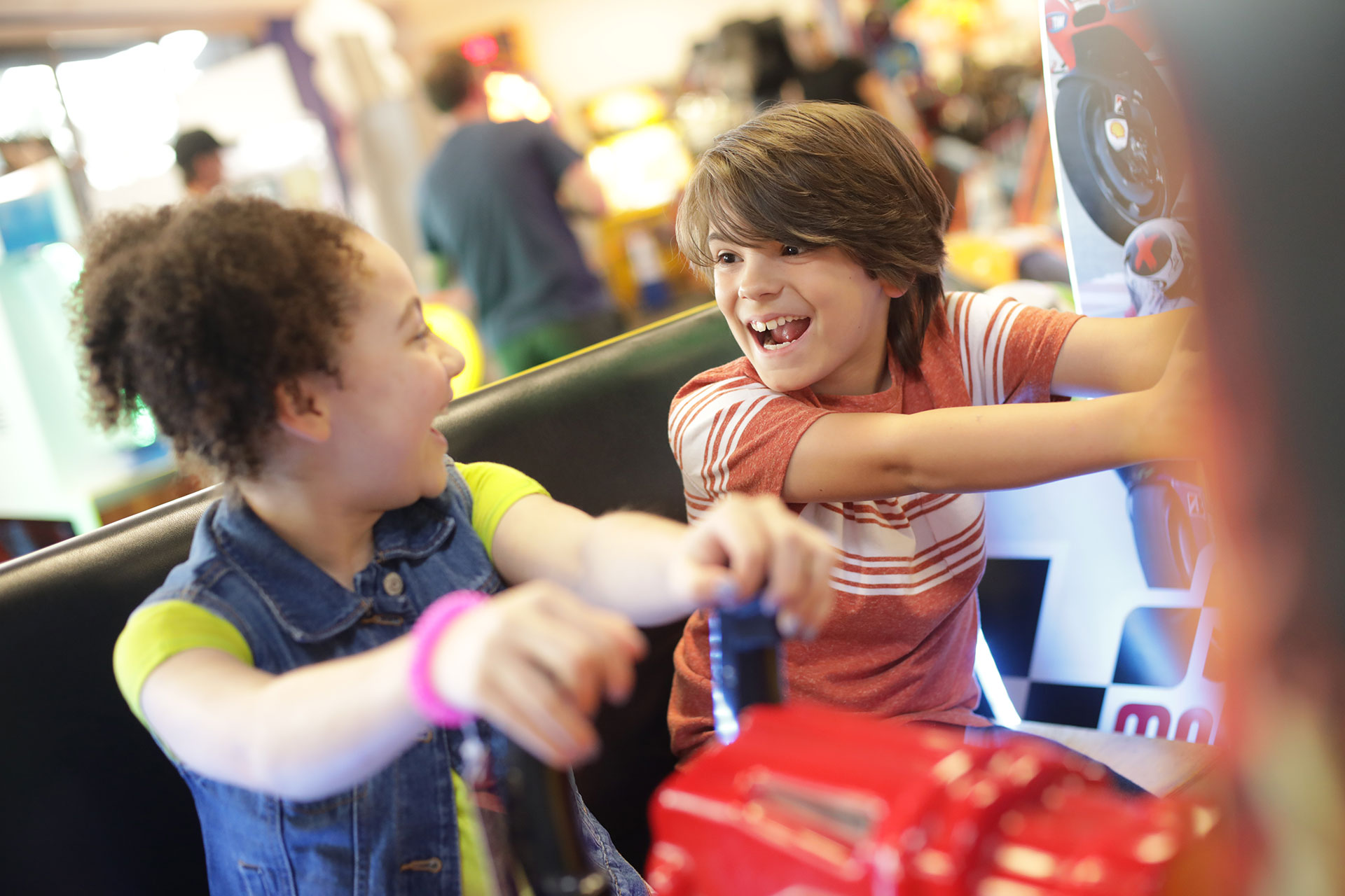 Kids playing arcade game smiling at each other